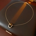 Detalle del collar con colgante de ojo de tigre en acero de titanio sobre estuche marrón - Dorado
