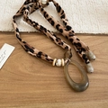 Macro detail of leopard print fabric strap with resin oval ring and wooden beads necklace - Leopard Print Amber Oval Style