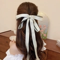 Detalle de un lazo de satén crema con ribete negro en el cabello largo y ondulado - Clip de resorte-Cinta multicapa beige