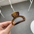 Detailed view of an amber resin hair claw clip with a glossy translucent brown finish - Matte Tortoiseshell