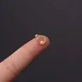 Delicate gold C-shaped tragus piercing with pearl and zircon detail on fingertip - Diamond-Encrusted Pearl Crescent (HSPJ356-9#G)