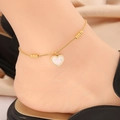 Détail d'une chevillère en or avec perles et pendentif cœur blanc sur mannequin - Forme de Cœur