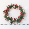 Dettaglio mini ghirlanda di Natale con aghi di pino e bacche rosse accanto a un metro - Bacche rosse con neve