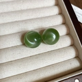 Detalle macro de pendientes de bola verdes brillantes en un joyero de color beige suave - Verde