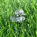 Miniature hand-carved duck statue made of mottled green gemstone on green grass - Green Spot Jasper