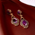 Dettaglio degli orecchini ovali vintage in oro con pietre viola su tessuto di raso rosso - Perno in Argento Oro Viola