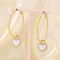 Detalle de pendientes de corazón dorados con esmalte blanco sobre seda beige - Dorado Blanco