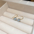 Makroaufnahme von grauen Perlenohrringen mit eleganten goldenen S-Haken in einer Box - 8mm Graue Perle Goldener Ohrhaken