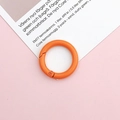 Close-up of a 25mm bright orange lacquered metal spring ring for DIY jewelry making - Orange