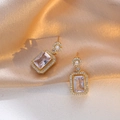 Detail of gold rectangular earrings with pink zircon stones on soft silk fabric - White Zirconia Earrings