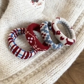 Gros plan de quatre chouchous tricotés en rouge et bleu sur un fond de pull moelleux - Série Rouge et Bleu (Lot de 4)