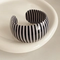 Detalle de brazalete ancho con rayas blancas y negras en una bandeja de cerámica blanca - Rayas Verticales Negro Blanco