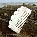 White shell comb with carved hollow design on a beach rock by the seaside - Auspicious Cloud Comb