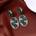 Vue macro de boucles d'oreilles fleurs émeraude vintage sur satin avec une assiette - Gris Anthracite-Vert