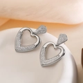 Orecchini a cuore d'argento con zirconi scintillanti su un piatto di ceramica bianco - Argento
