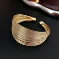 Vista macro del bracciale rigido multistrato placcato oro con finitura a filo testurizzato - Oro