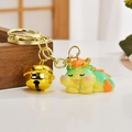 Cute green resin dragon keychain with golden bell charm on a vintage wooden box - Sleepy Dragon Style