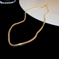 Detailansicht einer vergoldeten Schlangenknochen-Choker-Kette auf schwarzer Fläche - Gold