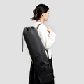 Black yoga mat bag with drawstring closure and adjustable strap shown on model back - Black