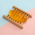 Handmade transparent yellow oval soap on a natural wooden dish with blue and pink backdrop - 110g Thai-style Calendula Soap