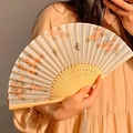 Classic folding bamboo fan with traditional flower and bird pattern held by hand - Peach Orchard