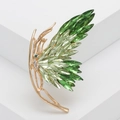 Spilla a farfalla dorata con cristalli verdi sfumati su piedistallo bianco elegante - Verde