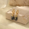 Detalle de pendientes de aro dorados con piedra azul y colgantes de estrella en base - Redondo Plano Azul Oscuro