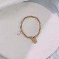 Close-up of golden beaded bracelet with white pearl and monstera leaf pendants - Gold-Foliage