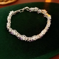 Close-up of silver-toned tennis bracelet with purple zircons on green velvet background - Purple