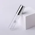 Dettaglio flacone spray in vetro da 10ml con tappo argento e stampa di foglie grigie - Stile Linea di Taglio / Argento