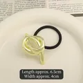 Elastic hair tie featuring a polished gold metal knot accessory on a black band - Knotted Design Gold