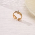 Macro detail of golden twisted band ring featuring a sparkling zircon cross design - Twisted Rope Texture Cross Design