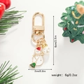 Detailed view of enamel snowman keychain with faux pearl and holiday decorations - Snowman with Broom