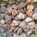Detailed view of numerous heart-shaped natural stones with red-brown marble patterns - Red Network Stone