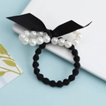 Elegant black wavy hair tie with white pearl bow and ribbon on a clean white tray - Pearl Bow with Wave Tie