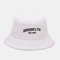 Dettaglio del ricamo nero Brooklyn EST 1634 su un cappello a secchiello in tela bianca - Taglia unica / Bianco