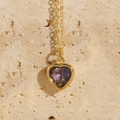 Gold chain heart necklace with purple zircon pendant displayed on natural stone - Purple