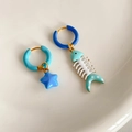 Dettaglio di orecchini asimmetrici con stella blu e lisca di pesce in smalto e metallo - Stile Lisca di Pesce e Stella Marina Blu
