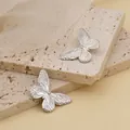 Detailaufnahme von Schmetterlingsohrsteckern in Silberoptik auf Steindisplay - Silber