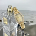 Close-up of luxury gold tonneau watch with crystal bezel resting on perfume bottle - Gold