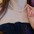 Gros plan d'un choker en perles avec pendentif doré porté sur le cou d'un modèle - Collier De Perles Rondes Blanches