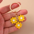 Daisy flower keychain with three yellow charms and gold metal chain on a beige background - Yellow