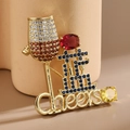 Vista macro de broche de copa de vino dorado con circonitas y detalle de Cheers - Morado