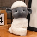 Cute gray and white plush sheep slap bracelet toy on a wooden table setup - Sitting Lamb