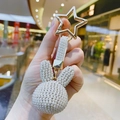 Detailed close-up of a white pearl rabbit keychain with a golden star-shaped metal clasp - White
