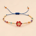 Dettaglio del bracciale di perline colorate con ciondolo a fiore e cordino blu regolabile - Fiore Rosso Con Perline Dorate
