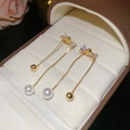 Detail von langen Gold-Quastenohrringen mit Strass-Schleife und Perle in Schmuckbox - Gold Perle Schleife Stil / Gold