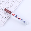 GuangNa brown oil-based paint marker with 2.8mm tip on white laptop keyboard - Coffee