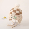Detail van gebreide babymuts met oorkleppen, ruitpatroon en schattige beren-patch - Beige Schaakbord Beer Stijl / Beige