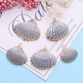 Cinque ciondoli a forma di conchiglia con trama argento e bordo dorato su fondo blu - Tessitura Argento